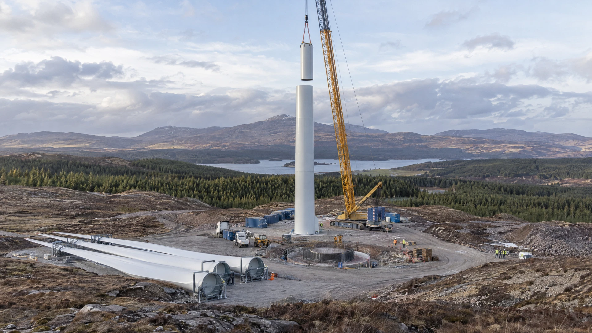 AI-generated illustrative concept of an unfinished wind installation with a partially erected tower, crane and safely staged blades; not a verified EJ Legacy Energy site.