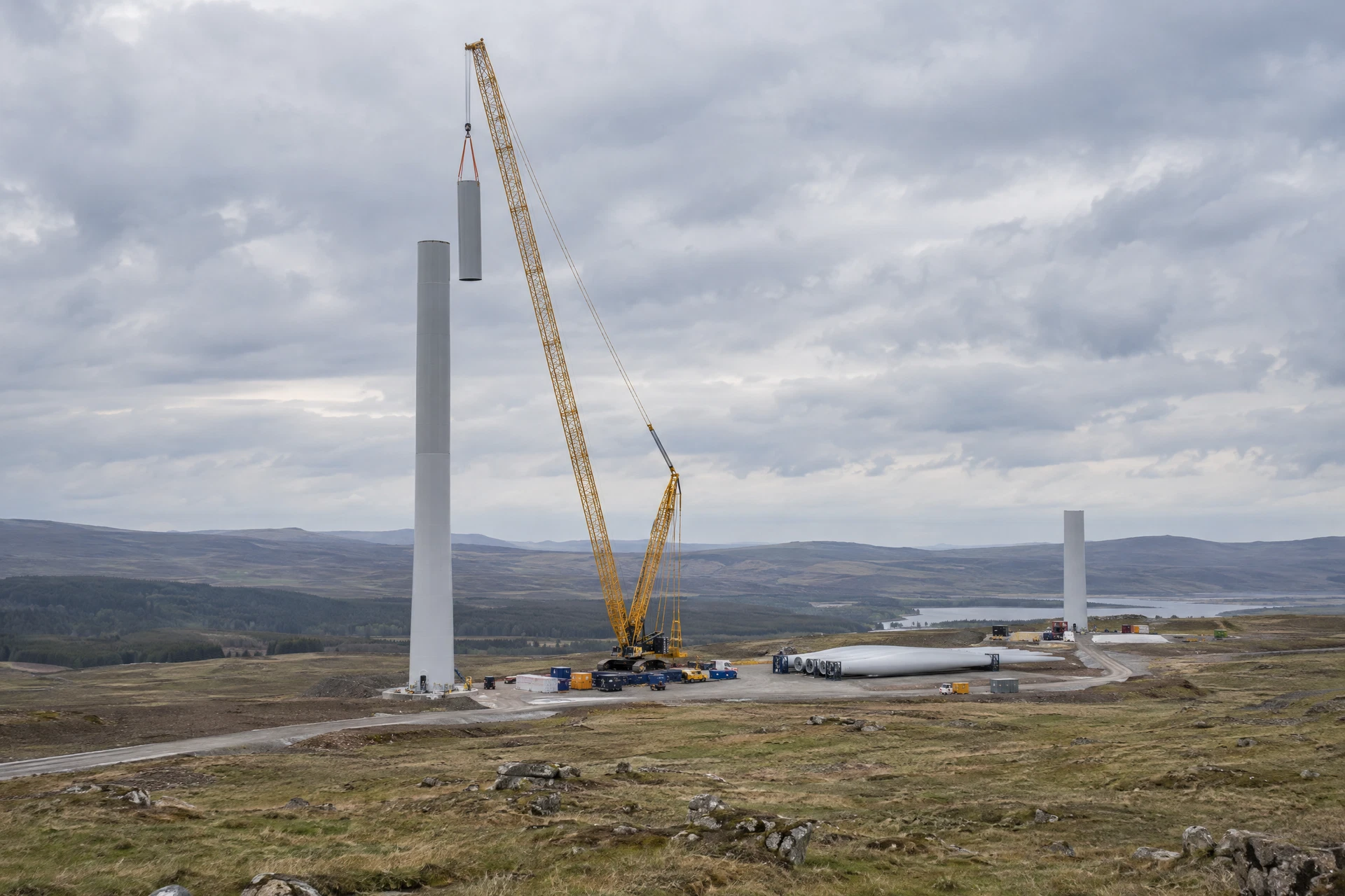 Illustrative view of a partly erected wind-turbine tower being assembled with a crane; not a verified company site.