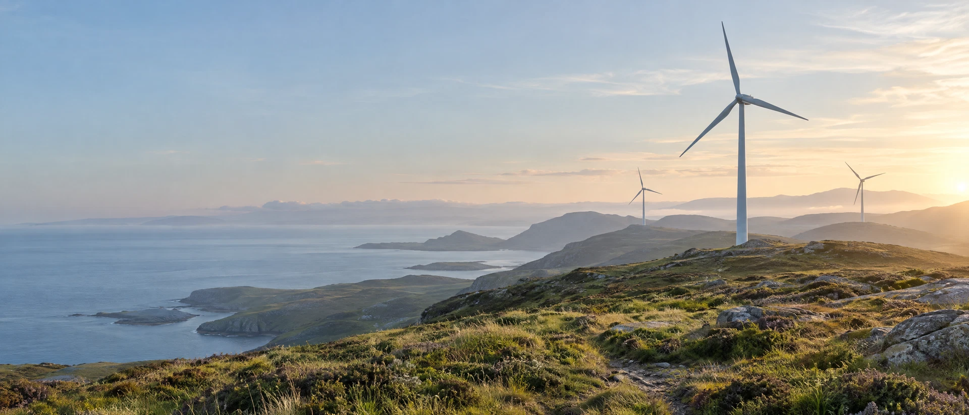 Wind turbines standing across rolling green uplands beneath the morning sky